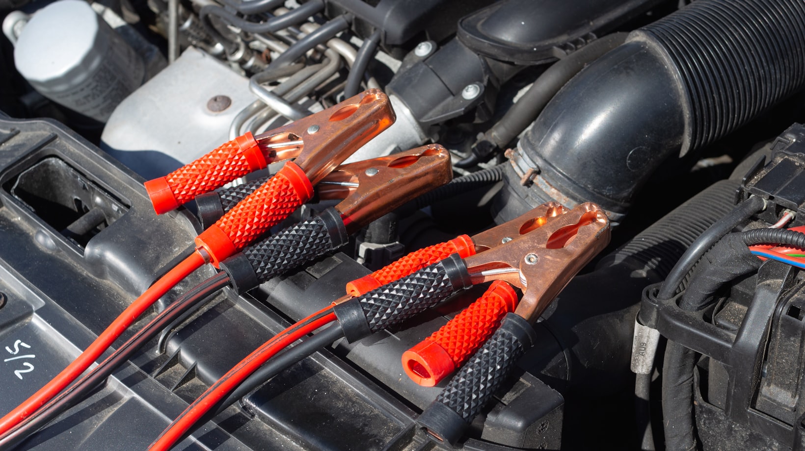Jumper cable clamps resting on the engine bay of a German car